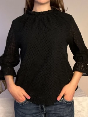 Svart spetsblus med trekvartsärm, Carin Wester🖤 - Snygg svart blus i genombruten spets med rundad hals och trekvartsärmar. Blusen har en avslappnad passform och voluminösa ärmar med lätt rynk vid axlarna. Perfekt att styla med jeans eller kjol för en trendig look.🖤