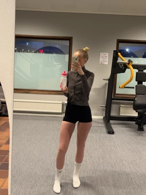 Grå zip-tröja med ribbad struktur - Säljer en grå zip-tröja med ribbad struktur och hög krage. Tröjan har långa ärmar och en smal passform, perfekt för gymmet eller träning. Materialet är stretchigt och bekvämt för rörelse.