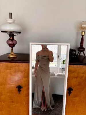 Balklänning - Superfin grön/beige off-shoulder balklänning i satin. Insydd korsett upptill så den sitter väldigt bekvämt, slits framtil och den där draperad, se bild 3 för färgen i dagsljus💕Endast testad