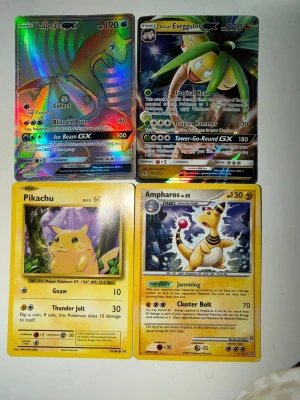 Pokémon samlarkort Lapras GX m.fl. - Fyra Pokémon samlarkort: Lapras GX och Alolan Exeggutor GX med glansig holografisk yta, samt klassiska Pikachu och Ampharos i gul design. Perfekt för dig som gillar att samla eller spela Pokémonkort. Kort i olika färger och med detaljerade illustrationer.