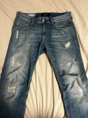 Blåa Replay anbass jeans  - Säljer ett par blåa Replay anbass jeans med slitningar. Storleken är W31 L32. Modellen på bilden är 183 cm o väger ca 70 kg. Skev vid minsta fundering.