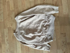 Beige sweatshirt i bomull - En enkel och stilren beige sweatshirt med rund hals och långa ärmar. Tillverkad i mjuk bomull och har ribbade muddar vid ärmslut och nederkant. Perfekt för en avslappnad look.
