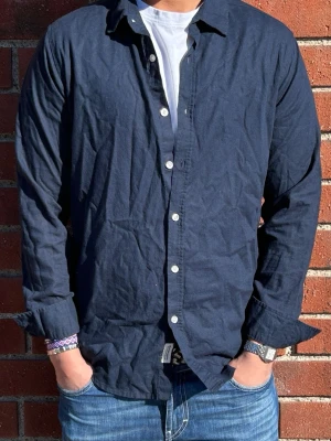 Marineblå Linneskjorta  - Marineblå linneskjorta | Storlek: S - Skicket pa skjorta är  bra med lite tecken på användning - Varat pris: 100 - Modellen är 180cm och väger 70kg.