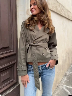 Kort khakigrön trenchcoat med bälte - ! INTRESSEKOLL! Så så fin trenchcoat ifrån Gina helt ny prislappen kvar, skriv om ni har intresse och kom gärna med bud!💓säljer för högre pris då den är efterfrågad och helt slutsåld 