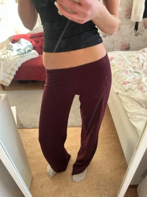 Vinröda mjukisbyxor med utsvängda ben - Säljer ett par vinröda mjukisbyxor med utsvängda ben och hög midja. Byxorna har en enkel, stilren design utan synliga fickor eller loggor. Perfekta för chill dagar hemma eller när du vill ha det extra bekvämt.