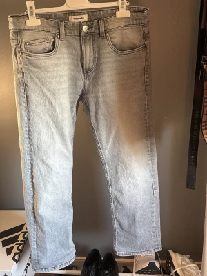 Ljusgrå raka jeans från Kappahl - Säljer ett par ljusgrå jeans från Kappahl med rak passform och klassisk femficksdesign. Jeansen har normal midja och är tillverkade i ett mjukt denimtyg. Perfekta för en avslappnad och trendig look.