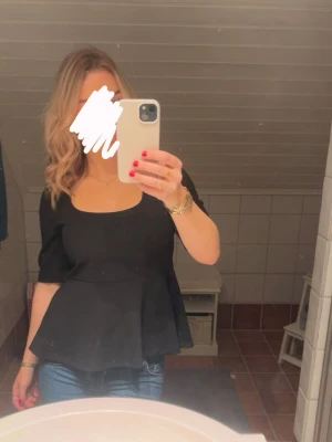 Svart  topp med fyrkantig ringning - Snygg svart  topp med fyrkantig ringningen och halvlånga ärmar. Toppen har en tajtare  midja och är utsvängd nedtill. Skitsnygg!