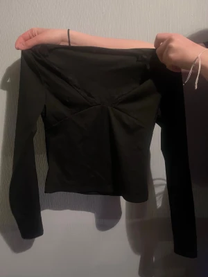 Svart långärmad topp med spetsdetalj - Snygg svart långärmad topp med en subtil spetsdetalj vid bysten. Modellen är croppad.