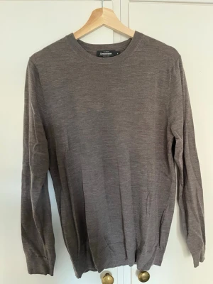Brun stickad tröja från Dressmann - Säljer en stilren brun stickad tröja från Dressmann. Tröjan har rund halsringning, långa ärmar och ribbade muddar vid ärmslut och nederkant. Perfekt för lager på lager och enkel att matcha med olika outfits.
