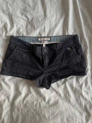 Abercrombie & Fitch Shorts - Gulliga shorts från abercrombie & fitch, köpt secondhand säljer då dom är förstora, har aldrig använt dom. Skulle säga att de är storlek S. Lite fundersam över färgen men de är antingen mörkblåa eller mörkgråa. Midjemått: 38 cm tvärs över, midjehöjden: ca 19,5 cm.
