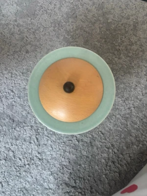 Mintgrön sockerskål från Höganäs  - Säljer en stilren sockerskål i mintgrönt porslin med ett runt lock i ljust trä och svart knopp. Enkel och modern design som passar in överallt.