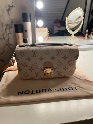 Louis Vuitton beige monogram handväska - Snygg beige handväska från Louis Vuitton med klassiskt monogrammönster i brunt. Väskan har guldfärgat lås framtill, svart handtag och avtagbar axelrem. Pris kan diskuteras vid seriöst intresse. Säljes då den ej kommer till användning.