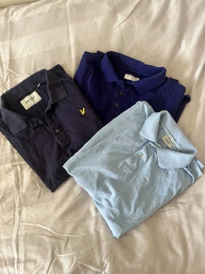 3 pikétröjor från Boomerang, tiger of Sweden och Lyle & Scott - Säljer tre pikétröjor i olika färger: ljusblå från Boomerang, mörkblå från Tiger of Sweden och en marinblå från Lyle & Scott. Alla har klassisk krage och knappar framtill. Perfekta för en clean och stilren look. 