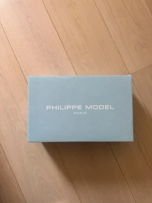 Blå Philippe Model bytes - Snygga blå sneakers från Philippe Model i mocka med beige detaljer och vita snören. Skorna har en låg profil och en vit, något sliten sula. Klassisk design med märkets logga på sidan och metallöljetter för snörningen.