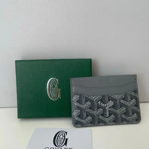 Grå kortfodral  - Snyggt grå kortfodral med det klassiska vita mönstret. Tillverkat i tåligt canvasmaterial med flera fack för kort. Perfekt för dig som vill ha en stilren och exklusiv accessoar i fickan. Helt nytt, fraktar inom 24 timmar.
