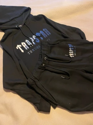 Svart Trapstar tracksuit - Säljer ett svart loungewear set från Trapstar med hoodie och matchande byxor. Tvättar och fixar till de innan de skickas! Om ni vill att jag försöker fixa något annat med de så är det ba era säga till! Eller om ni skulle ha någon annan fråga!!