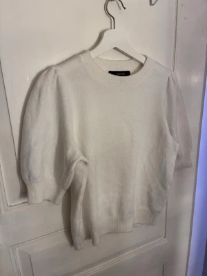 Vit puffärm stickad tröja Vero Moda - Säljer en vit stickad tröja från Vero Moda med puffärmar och ribbade muddar vid ärmslut och nederkant. Tröjan har rund halsringning och är gjord i ett mjukt material som känns skönt mot huden. Perfekt för dig som gillar en enkel men trendig look.