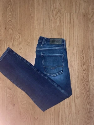 Blå anbass jeans från Replay - Snygga blå skinny jeans från Replay med klassisk femficksdesign och diskreta slitningar framtill. Jeansen har normal midja och är tillverkade i stretchigt denim för en bekväm passform. Perfekta till en avslappnad streetstyle-look.