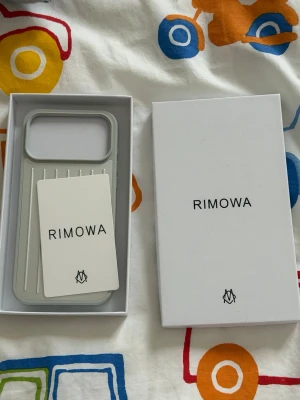Rimowa skal 17 PRO  - Stilrent grått mobilskal från Rimowa med räfflad design och robust känsla. Skalet är gjort i hårdplast och har en snygg, minimalistisk look. Perfekt för dig som vill ha ett exklusivt och modernt skydd till din mobil.