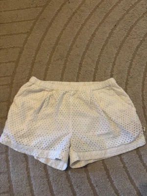 Vita lågmidjade spetsshorts🩷 - Säljer ett par vita lågmidjade  shorts med elastisk  och snyggt hålmönster i broderad stil. De är tillverkade i ett lätt tyg som känns luftigt och passar perfekt till sommaren. Shortsen har en avslappnad passform och är riktigt bekväma. strl 146/152 men passar xs/s