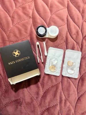 Bruna cosplay- årliga linser från Saza Cosmetics - Säljer ett set med bruna färgade kontaktlinser från Saza Cosmetics, perfekt för maskerad och cosplay. Setet inkluderar linser, linsbehållare, pincett och applikator. Linserna har en naturlig brun ton och kommer i originalförpackning.