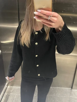 Svart kofta med guldfärgade knappar - Snygg svart kofta med guldfärgade knappar framtill. Något nopprig, storlek XL men passar xs-m🩷