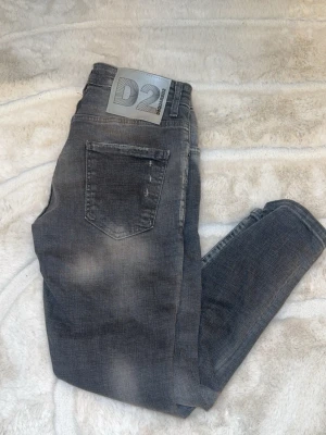 Grå slim fit  jeans från Dsquared2 - Säljer ett par grå slim fit från Dsquared2 med slitningar och tvättade detaljer. Jeansen har fem fickor, normal midja och en snygg, smal passform. Perfekta för dig som gillar en trendig och avslappnad stil.