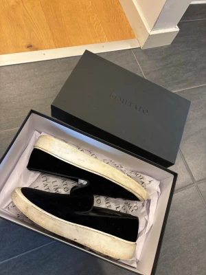 Svarta loafers från Limitato - Säljer ett par svarta loafers från Limitato med vit, tjock sula. Skorna har en stilren slip-on design och är tillverkade i mjukt sammetstyg som ger en lyxig känsla. Perfekta för dig som vill ha en clean och modern look. Även perfekta till sommaren, studenten, bal mm. PRISET är disskuterbart, lämna bud