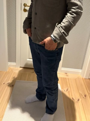 Blå raka jeans från Morris Stockholm - Säljer nu dessa klassiska blå jeans från Morris Stockholm med rak passform och fem fickor. Jeansen har en snygg lätt tvättad look och är tillverkade i ett mjukt denimtyg som är skönt att bära. Perfekta till en avslappnad stil. Storlek W28/L33. Jeansen är i mycket bra skick och nypriset är ca 1400 kr.