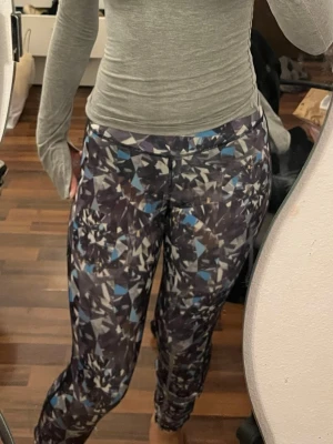 Mönstrade leggings med geometriskt tryck - Säljer ett par leggings med coolt geometriskt mönster i svart, grått, vitt och blått. De har hög midja och sitter tight, perfekta för dig som vill ha något unikt och bekvämt. Materialet känns stretchigt och mjukt, passar perfekt till en avslappnad stil.