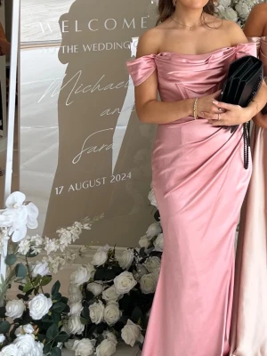 Balklänning - Rosa offshoulder långklänning - Snygg långklänning i ljusrosa satin med offshoulder och draperad överdel. Klänningen har en figurnära passform och en slits på sidan som ger extra attityd. Perfekt för bal eller student och ger en elegant siluett.