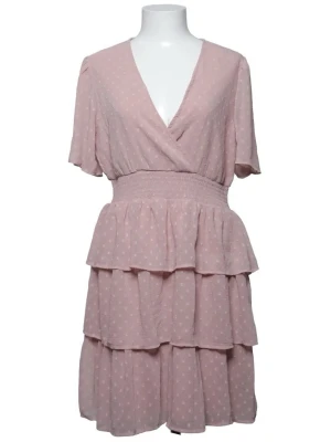 Ljusrosa prickig omlottklänning - Söt ljusrosa kortklänning med vita prickar och omlott överdel. Klänningen har v-ringning, korta ärmar och markerad midja med smock. Kjolen har dubbla volanglager för extra flow. Perfekt för sommarens alla tillfällen.