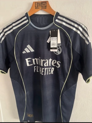 Real Madrid matchtröja player edition  - Mörkblå Real Madrid bortatröja från Adidas med Carvajal och nummer 2 på ryggen. Tröjan har vita detaljer, klubbmärke och sponsortryck framtill samt klassiska Adidas-ränder på axlarna. Tillverkad i lätt och ventilerande material, perfekt för fotbollsträning eller match. Såklart äkta, player edition betyder att den är bättre en vanligt, det är den tröjan spelarna spelar med 👌✅