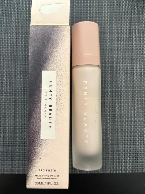 Fenty Beauty Pro Filt’r Primer - Fenty Beauty Pro Filt’r Mattifying Primer i en frostad glasflaska med ljusrosa lock. Primern är 30 ml och ger en matt finish som minskar glans och suddar ut porer. Snygg och stilren design, perfekt för dig som vill ha en jämn bas.