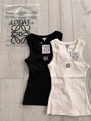 Ribbad linnetopp från L - Två ribbade linnetoppar från Loewe i svart och vit. Båda har rund halsringning och Loewe-logga broderad framtill. Perfekta att styla lager på lager eller bära som de är. Materialet känns mjukt och stretchigt.