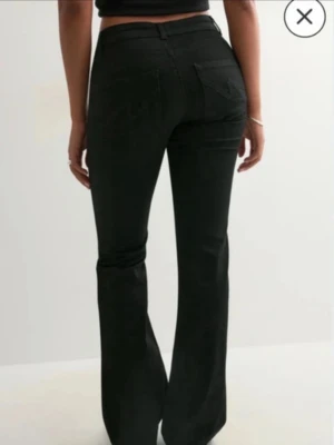 Svarta bootcut jeans med låg midja - Säljer ett par svarta bootcut jeans med låg midja och klassisk femficksdesign. Jeansen har utsvängda ben och är tillverkade i ett stretchigt denimtyg som sitter snyggt. Perfekta för dig som gillar en tidlös och trendig look. Nypris 699:-
