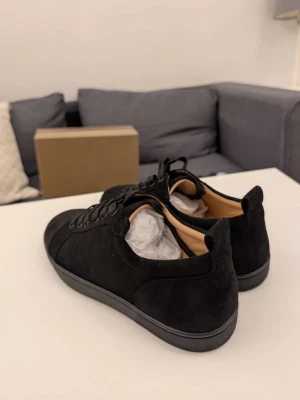 Christian louboutins no studs - Stilrena svarta sneakers i mocka med svarta skosnören och diskret sula. Klassisk låg modell som passar till det mesta. Insidan är ljus och skon har en enkel, modern design utan synliga loggor.