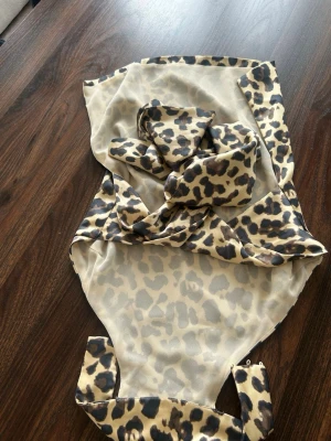 Leopardmönstrad mesh topp - Trendig topp i transparent mesh med leopardmönster. Modellen är ärmlös och har knytband som kan stylas på olika sätt. Materialet är lätt och stretchigt, perfekt för en edgy och cool look.