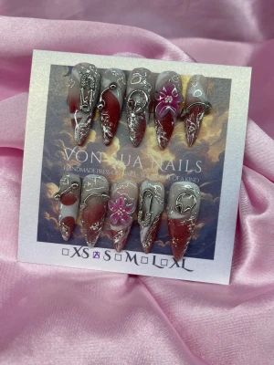 Lock (S);Long Stiletto  - Unika handgjorda press-on naglar i en lång stilettoform med röd och nude bas, dekorerade med silvriga 3D-detaljer, 3D nailart och rosa/röda blommor. Perfekt för dig som vill sticka ut med en edgy och konstnärlig look. S: 15 mm, 11,5 mm, 12 mm, 11 mm, 9 mm 