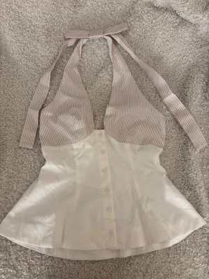 Topp - Fin topp med knappar framtill och öppen rygg, rosett detalj baktill. Toppen är figur sydd. Aldrig använd, därmed nytt sick! 