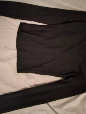 Svart långärmad topp - En enkel svart långärmad topp med rak passform. Perfekt att matcha med jeans eller kjol för en clean look. Tillverkad i mjukt material som känns skönt mot huden.