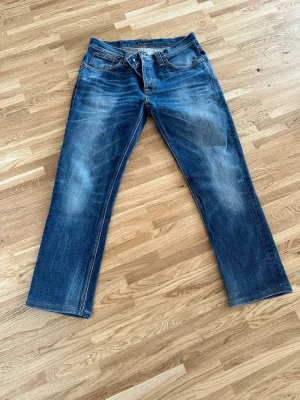 Blå raka jeans från Nudie Jeans - Säljer ett par klassiska blå jeans från Nudie Jeans med raka ben. Från modellen grim Tim. I storleken 34w och 32l passar någon som är runt 170cm