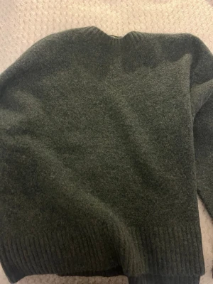 Mörkgrön stickad tröja Vero Moda. - Mörkgrön stickad tröja från Vero Moda med klassisk rund hals och ribbade muddar vid ärmslut och nederkant. Tröjan är mjuk och har en enkel, stilren design som passar perfekt till jeans eller kjol. Materialet är ullblandning för extra värme. Säljer eftersom det är fel storlek (helt oanvänd)