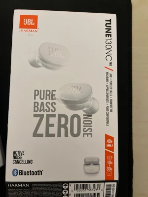 JBL Tune 130NC TWS trådlösa hörlurar - JBL Tune 130NC TWS är trådlösa in-ear hörlurar i vit färg med aktiv brusreducering och Pure Bass-ljud. De har Bluetooth, upp till 40 timmars batteritid och levereras med laddningsetui och extra öronproppar. Perfekt för musik och samtal på språng.