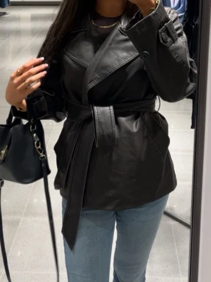 Svart skinnjacka med bälte - Snygg svart skinnjacka med bälte i midjan. Köpt från Gina.