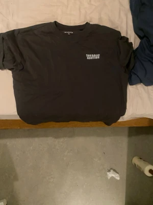 grå t-shirt  - Cool grå t-shirt från HM med texten 'THE DAILY ROUTINE' i retrostil på ryggen och mindre tryck fram. Skön passform och tillverkad i mjuk bomull. Perfekt för dig som gillar statement-plagg och vill ha en chill vibe.