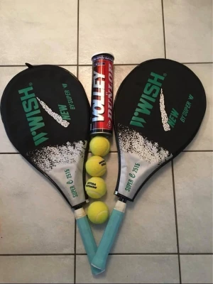 Tennisracketar och bollar set - Två svarta och gröna tennisracketar från Wish, en röd burk med Dunlop volleybollar samt tre gula Atoma tennisbollar. Perfekt för dig som vill spela tennis med kompisar. Racketarna har blått handtag och är av plast och metall.