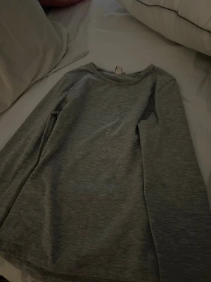 Grå basic långärmad tröja Nelly - En enkel och stilren grå långärmad tröja från Nelly. Tröjan har rund halsringning och är gjord i ett mjukt, tajt material som passar perfekt till alla typer av outfits. Jag säljer denna för den passar inte mig.