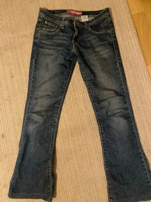Levi's 518 Superlow Bootcut Jeans - Säljer ett par mörkblå Levi's 518 Superlow Bootcut jeans med klassisk femficksmodell och snygga slitningar. Jeansen har låg midja och bootcut-ben, vilket ger en retro vibe. Tillverkade i bomull med lite stretch för extra komfort. Säljer pågrund av att dom är lite för korta på mig❤️
