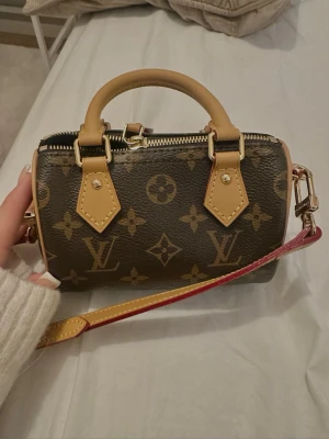 Louis Vuitton mini monogram väska - Säljer en liten handväska från Louis Vuitton i klassiskt brunt monogrammönster. Väskan har beige handtag och detaljer samt en avtagbar axelrem med röda kanter. Tillverkad i canvas med läderdetaljer och guldfärgade metalldelar. Perfekt för det viktigaste! Boxen sålde jag för nån månad sen så endast dustbag och annat tillbehör tillkommer.